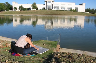 Student drawing across the lake from the Jule Collins Smith Museum of Fine Art