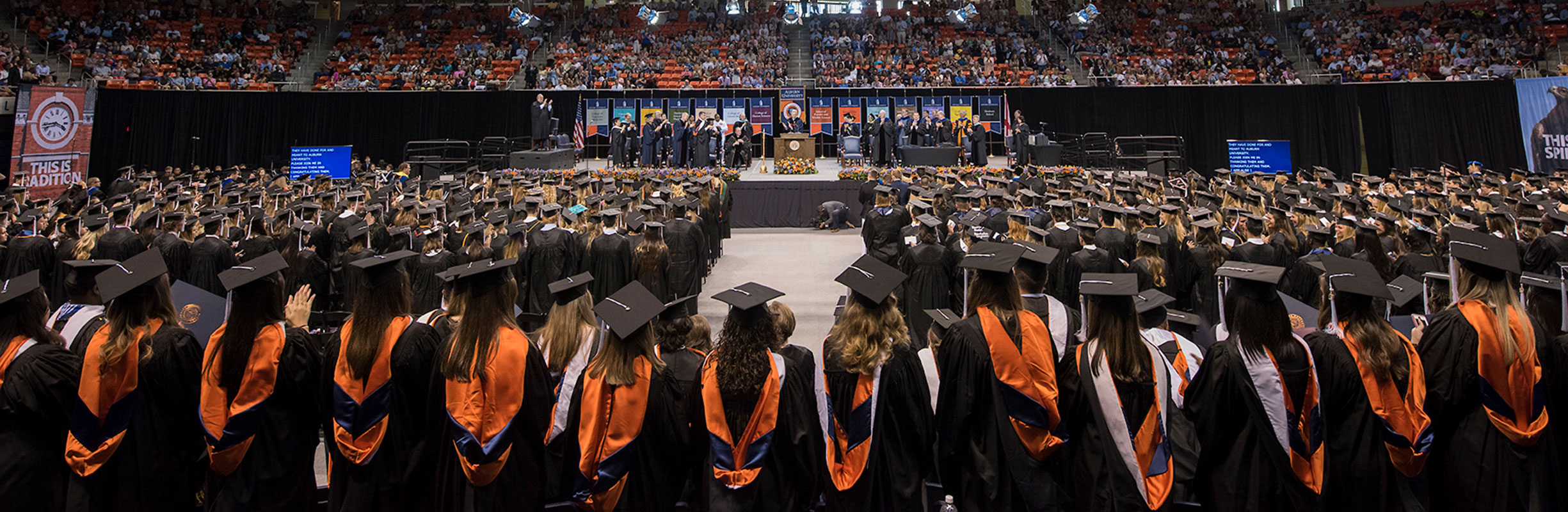 students in cap and gown applauding at graduation