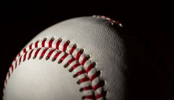 Closeup of a baseball half in shadow