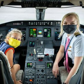 A pilot and young girl in the flight deck of a plane