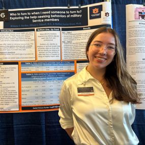 Brianna Gordon smiling next to research poster