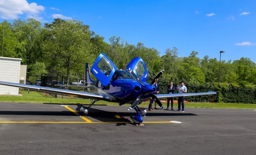 small blue plane parked on a runway with its doors open