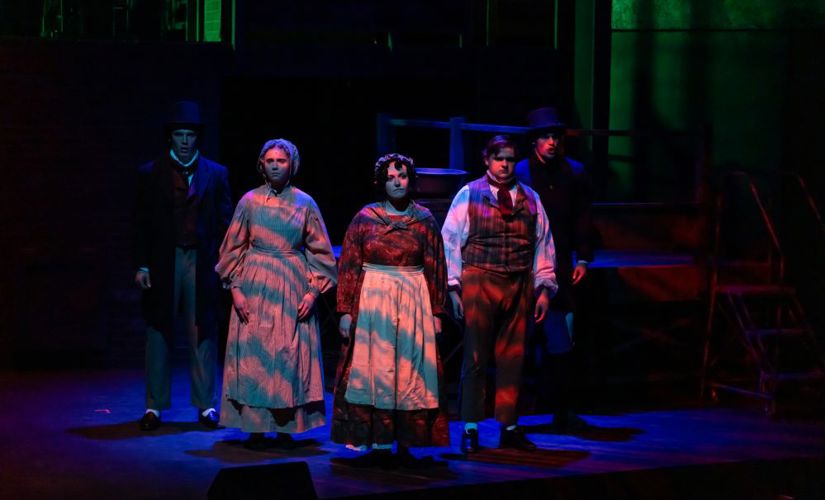 A lighting effect casts waves of blue and orange over a group of actors onstage