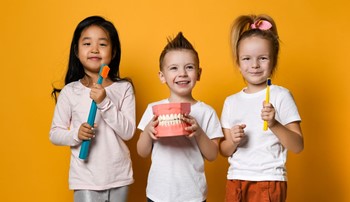 Kids holding toothbrushes and model teeth