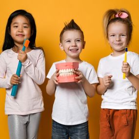 Kids holding toothbrushes and model teeth
