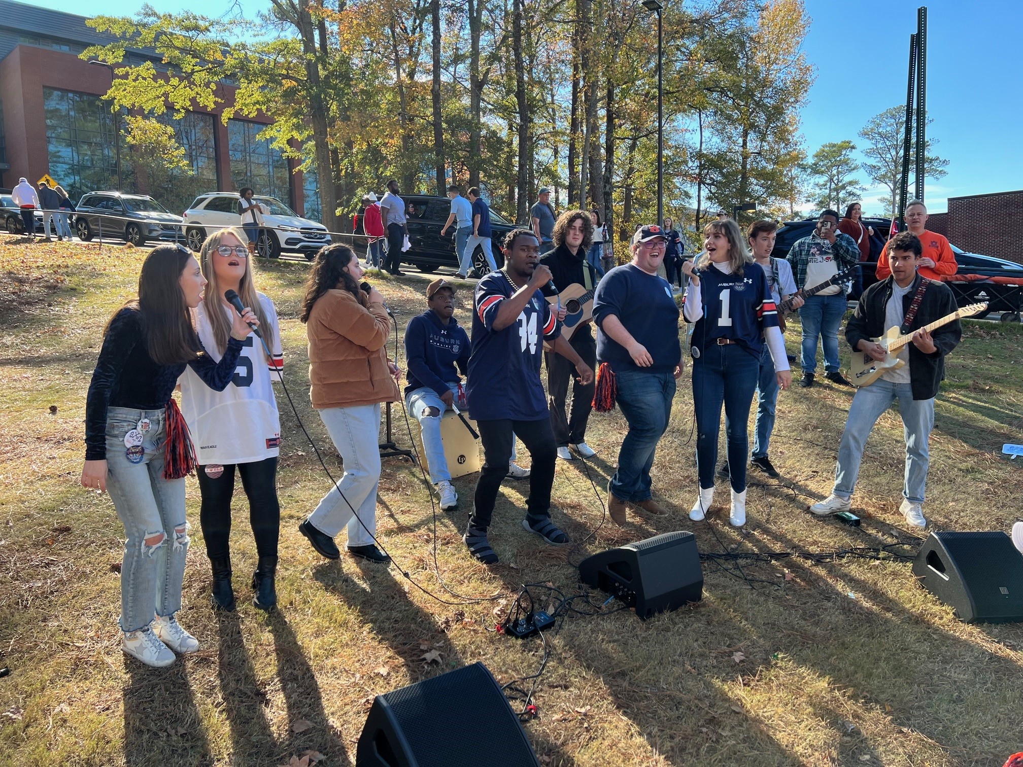 Several people stand around a microphone, speaking to an attentive audience in a vibrant public gathering.