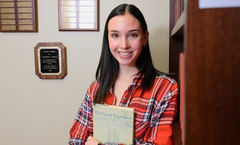 Emma Bond holds a copy of The Grand Expedition, a book written by her grandfather