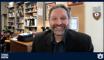 Professor Ed Youngblood smiles while recording a podcast