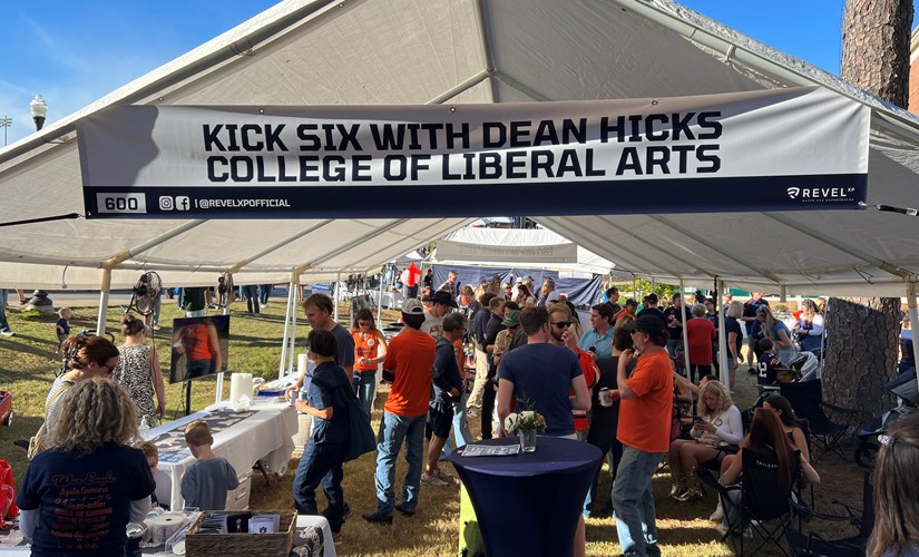 lively scene of Dean Hicks at the tailgate event, connecting with students and promoting engagement