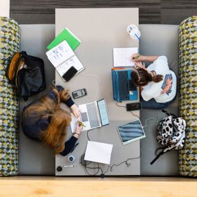 Aerial view of students using various electronic devices to complete coursework