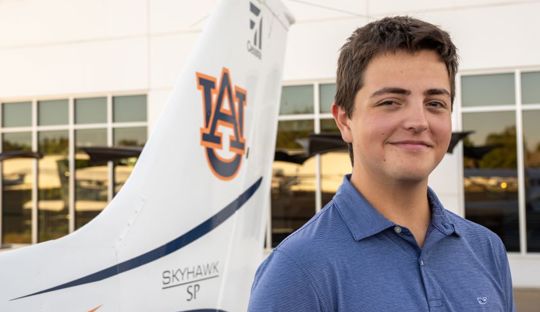 William Abbott posing for photo beside an Auburn airplane