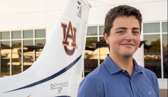 William Abbott posing for photo beside an Auburn airplane