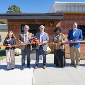 People cutting a ribbon in front of a building