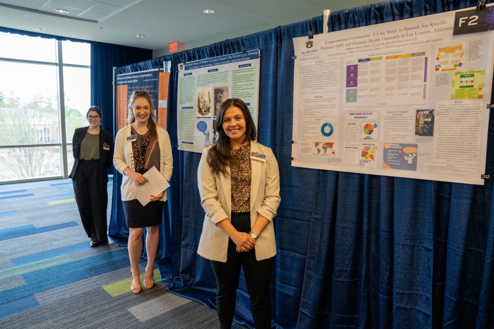 Three students pose with their poster presentations