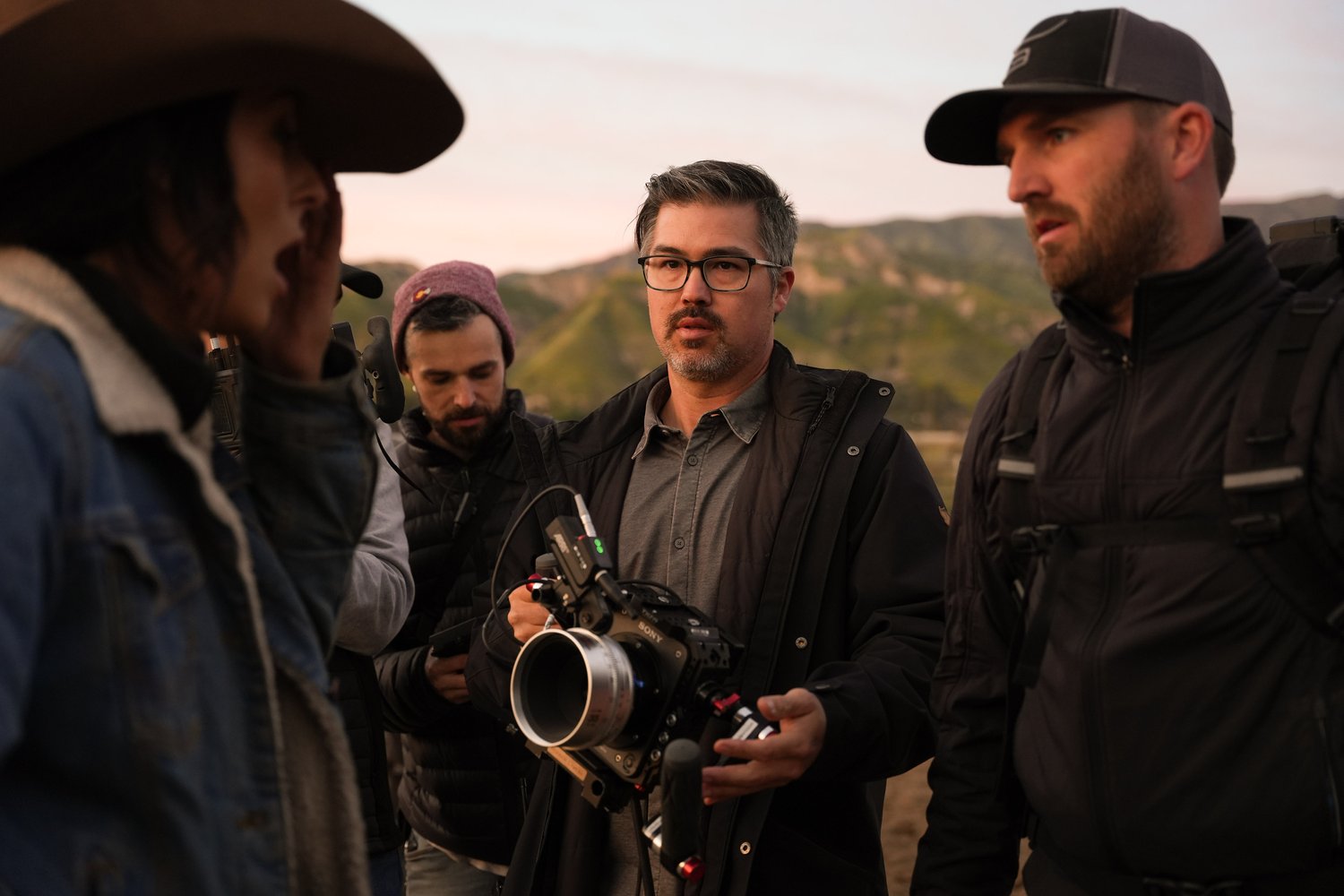 Matt Sakatani Roe holding camera and talking to actors on set