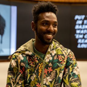 Kofi Bazzell-Smith in front of a digital display of his artwork