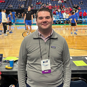 Daniel Locke posing for a photo courtside at the NCAA men's basketball tournament