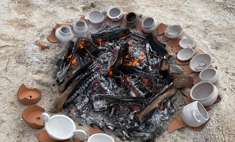 Image of the coals of a fire surrounded by clay pots 
