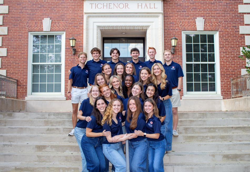 Group of students standing on stairs in front of a brick building