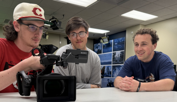 Students reviewing documentary footage on a camera
