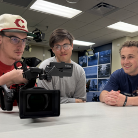 Students reviewing documentary footage on a camera