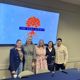 group of people standing in front of a screen with an image of the oaks agency logo