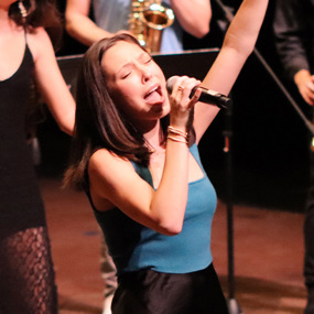 Anna Colson singing into a microphone during a performance