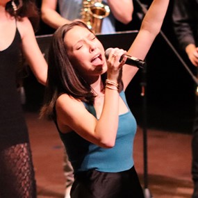 Anna Colson singing into a microphone during a performance