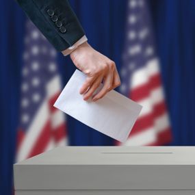 A citizen casting a vote into a polling box during an election.