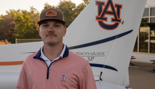 Nick Reyzin posing for photo in front of Auburn airplane