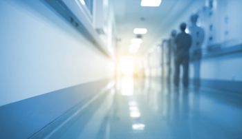 A silhouette of a medical professional walking down an unfocused hospital hallway
