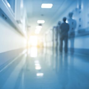 A silhouette of a medical professional walking down an unfocused hospital hallway