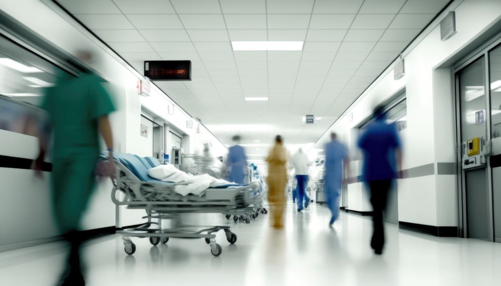 In a busy hospital, staff make the rounds and a gurney is wheeled down the hallway.