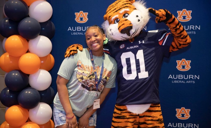 Student posing for a picture with Auburn's mascot, Aubie