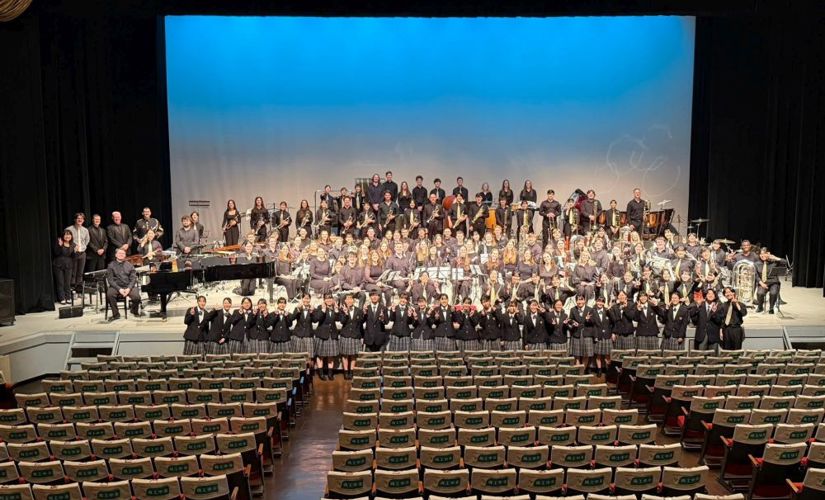 Auburn band students and Japanese high school band students on a stage in a large auditorium