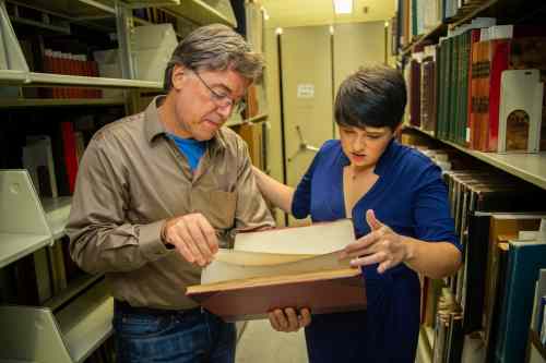 Two faculty looking at a book 
