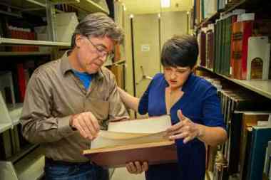 Two faculty looking at a book 