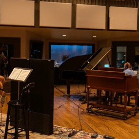 A man playing music in a vibrant recording studio filled with instruments and sound equipment.