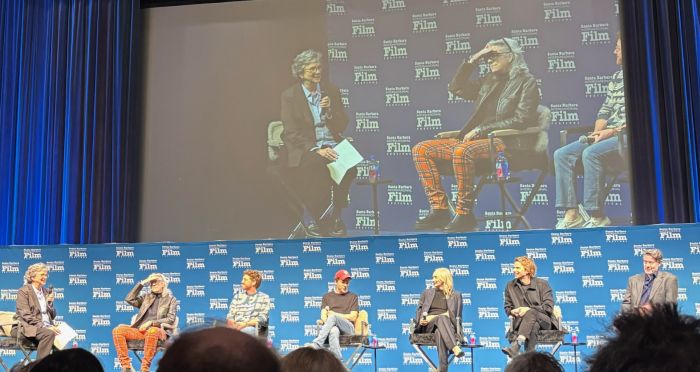 people sitting on a stage being interviewed by a woman