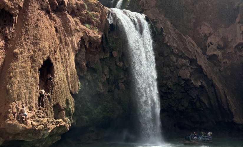 A waterfall rushing over large rocks into a pool