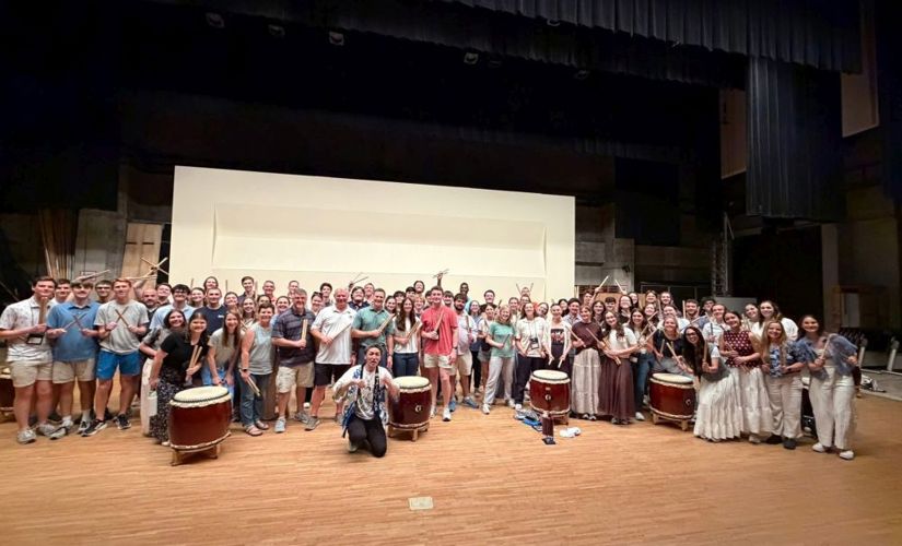 Band students posing with their instruments on a stage