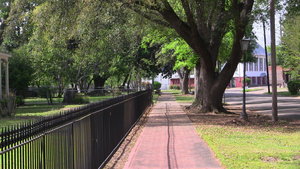 A red brick path trails along an iron fence