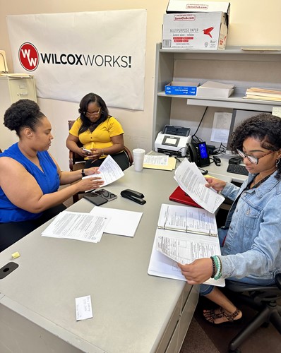 Women at Wilcox Works! review documents during a business meeting.