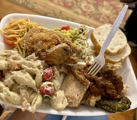 A plate filled to the brim of southern classics like pasta salad and fried chicken