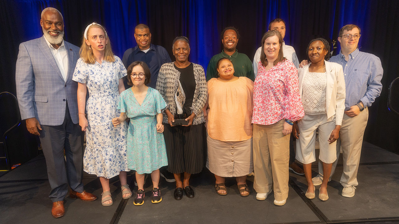 Angie Colvin Burque on stage with members of the BraveHearts program and Dr. Royrickers Cook