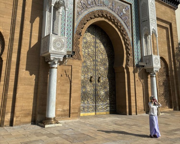 A woman posing for a photo in front of a towering ornate door