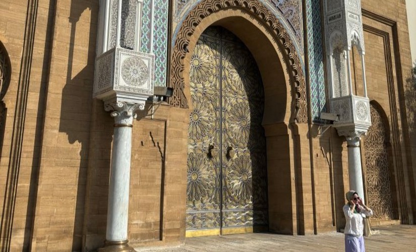 A woman posing for a photo in front of a towering ornate door