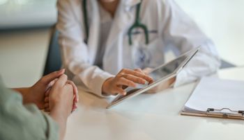 Patient listening as a doctor points at information on a digital tablet