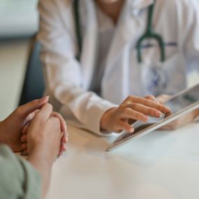 Patient listening as a doctor points at information on a digital tablet