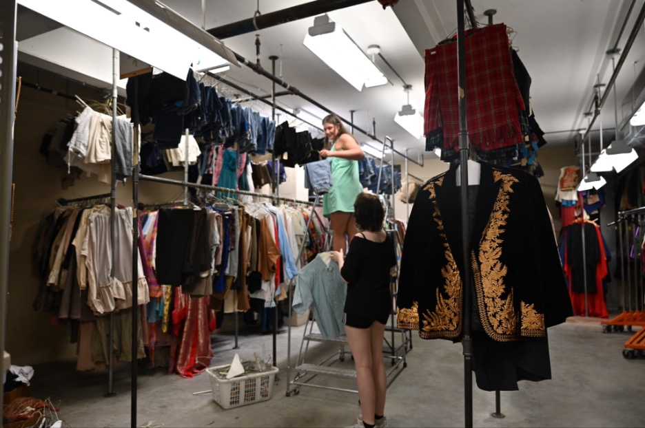 Catherine Govignon and Linnie Johnston restocking racks in costume shop storage.
